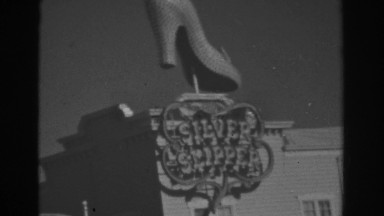 1962: amazing model of shoe displayed on the shop looked by a woman in bikini