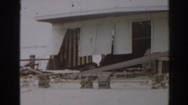 1963: people walking about what appears to be damage from a storm or hurricane