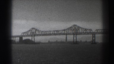 1937: bridge over a river next to a city with boats passing underneath it