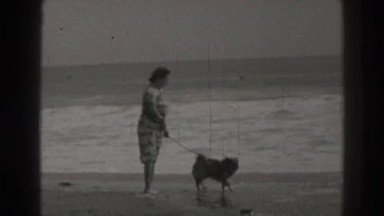 1937: lady playing in the beach with dog SANTA CRUZ CALIFORNIA