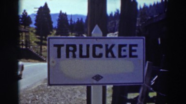 1937: a sign that reads truckee has a vehicle drive down the road past it