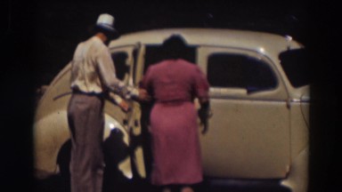 1937: man opening car door for women. TRUCKEE CALIFORNIA