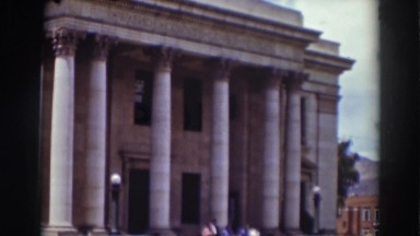 1937: row of columns stand in in front of gray stone building