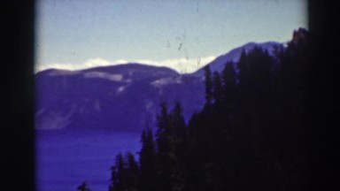 1937: mountain range with forrest in foreground overlooking lake CRATER LAKE