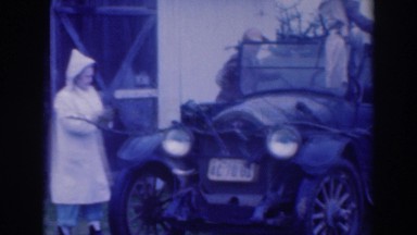 1937: group of people hand washing a vintage car next to their home at daytime