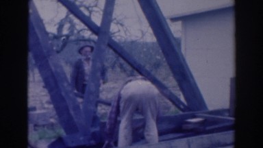 1937: men standing a man fixing something another holding something looking