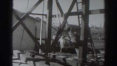 1937: men erect steel girders and beams atop tower next to completed structure
