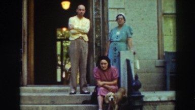 1937: family sitting out on the street corner with their dog. VIRGINIA CITY