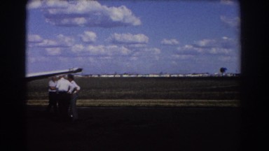 1967: men gather around a small aircraft at their country airport. BRISBANE