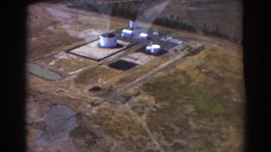 1967: a person, on a jet plane, is filming an oil refinement area. BRISBANE