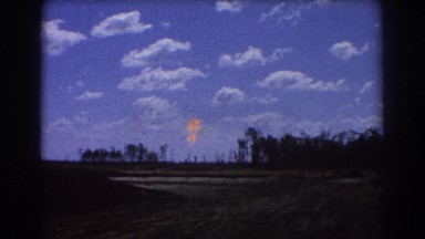 1967: open space with sparse trees and a flame going up BRISBANE AUSTRALIA