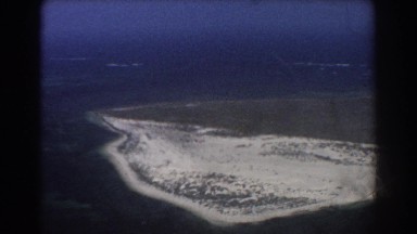 1967: big waves and sea foam crash on wide beach in shot from above PERTH
