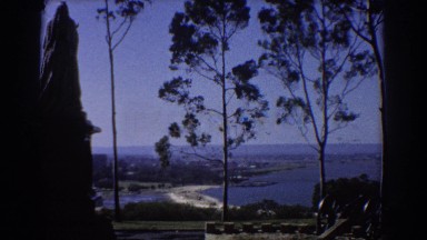 1967: scenic view across the water with a statue and an old cannon. PERTH