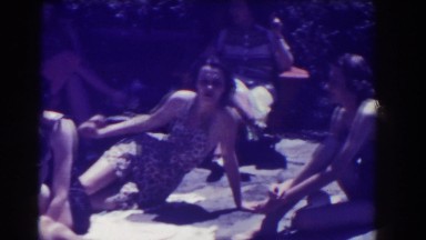 1937: people in bathing suits lounge outdoors in the sunshine while enjoying