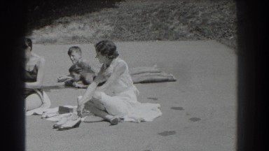 1937: group of people sitting on the ground outside in their bathing suits
