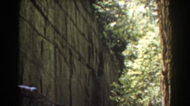 1939: big stone wall with narrow running brook with stones on a sunny day