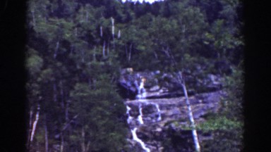 1939: A Tall Narrow Waterfall Runs Down a Forest Cliff at Mount Washington