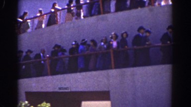 1939: a large group of people walking in a row by a helical ramp of a building