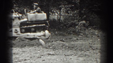 1938: Man Standing in Field with Machine Work in Progress
