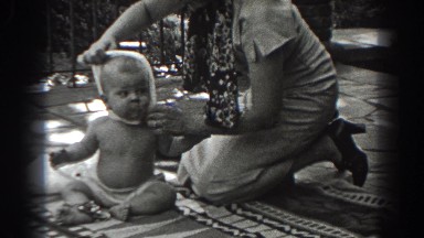 1938: mom struggling to take shirt off of her baby while sitting in the back