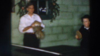 1957: two ladies playing ping pong while a man holds a small dog WHEELING OHIO