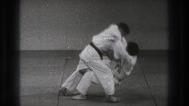 1971: two men wearing white are doing a karate move on each other on the floor.