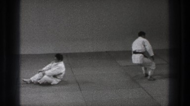 1971: two men standing to face one another before grabbing one another's arms