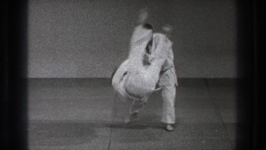 1971: two men grab one another by the shoulders and one of them is flipped then