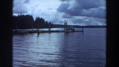 1964: a calm lake with bluish water and surrounded by mountain