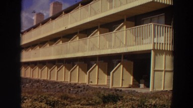 1964: lady standing at back of hotel observes the ocean shores. CALIFORNIA
