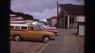 1964: sweeping view of trucks, white clapboard building with red trim, and snow