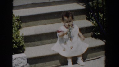 1960: Brother and Baby Sister Sitting on Steps Inspecting Garden