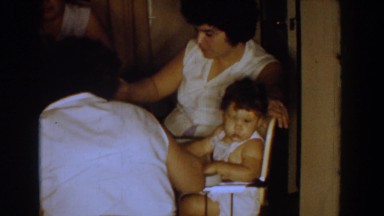 1960: mother feeds cute, distracted baby with a spoon of food BEL AIR MARYLAND