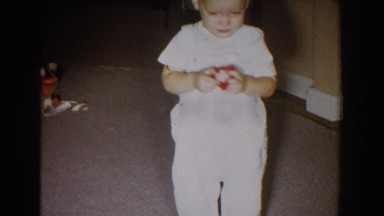 1965: toddler walking through the front room with a red toy. FALLSTON MARYLAND