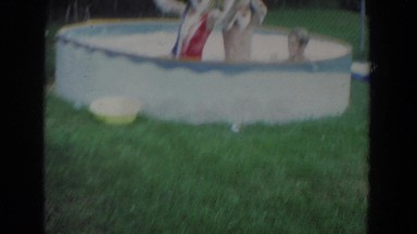 1965: children playing with friends in the swimming pool full of bubbles.