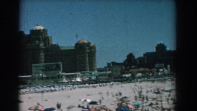 1958: beach with many people surrounded by large buildings in the back YORKTOWN
