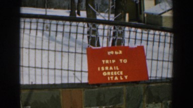 1962: A Sign on a Fence with White Lettering on It