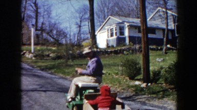 1964: A Dad Driving a Tractor Pulling His Kid in a Small Trailer Pequot Lakes