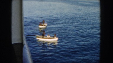 1960: Men Paddling Two Boats in the Ocean Next to a Ferry Miami, Florida