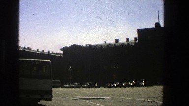 1975: a busy cross road at the side of the building on a sunny day with few cars