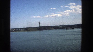 1975: Buildings Lining the Shoreline of Water with a Tall Building Behind