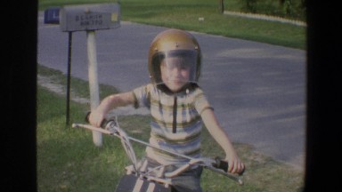 1973: Young Boy Sits atop Motor Scooter on Minnesota Porch