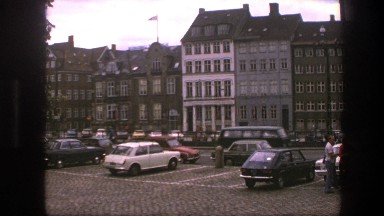 1975: town full of buildings with different faces and many vehicles all around