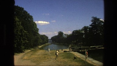 1975: a woman walking towards a large body of water next to a bridge COPENHAGEN