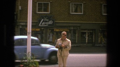 1975: people walk and cars drive down a city street near businesses COPENHAGEN