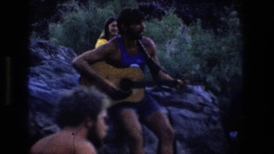 1969: people on the beach listening to a man play guitar UTAH