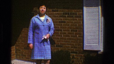 1969: person dressed up standing outside of a building waiting patiently