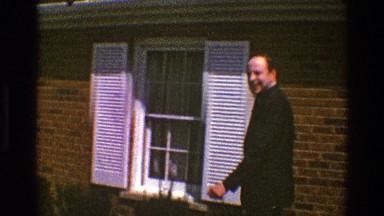 1969: a handsome man in formal dress wishing and entering a house CLARENDON