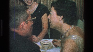 1968: a man kissing a womans cheek at a fancy party while sitting at a table