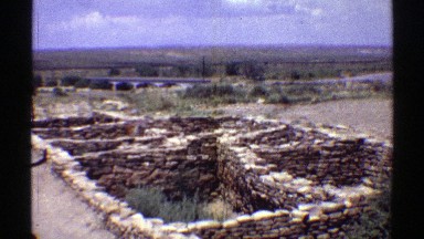 1969: a woman walking along what looks to be the ruins of a stone structure